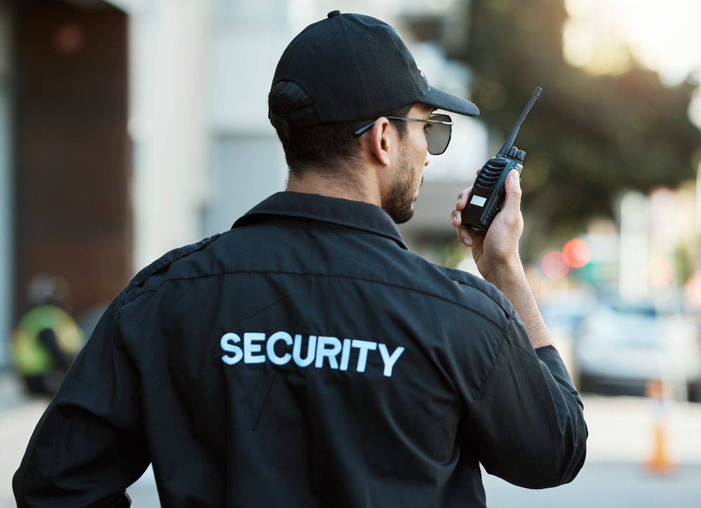 Security guard using radio during patrol illustrating cash flow and payroll management for security companies